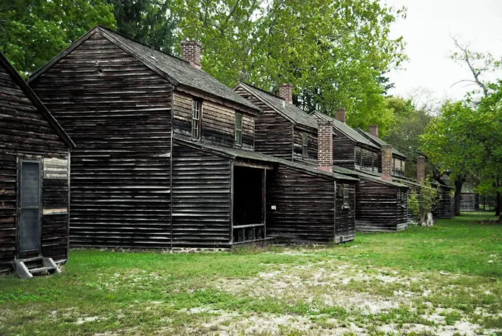 A row of weathered wooden workers' houses on a grassy lane at Batsto Village in the Pine Barrens