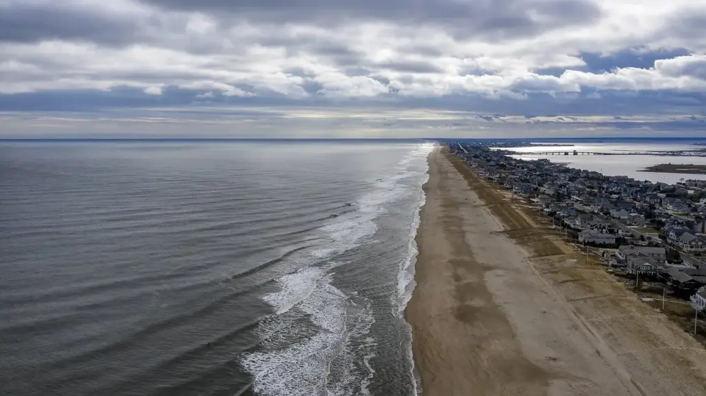 Aerial view of a long, empty beach at Bay Head with a row of houses behind the dunes and the ocean on the left