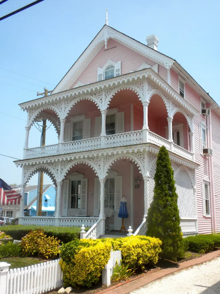 The Pink House in Cape May, a Victorian cottage with lacy white gingerbread trim on its two porches