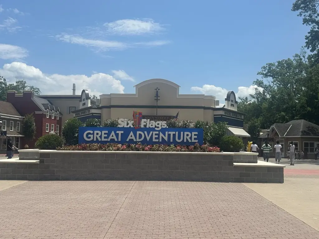 The park's name sign on a brick planter in the main entrance plaza, with the ticket buildings behind it