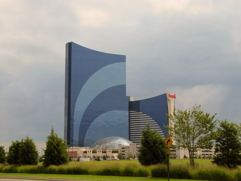 Harrah's curved blue glass hotel tower with a glass dome at its base, seen across a lawn and young trees