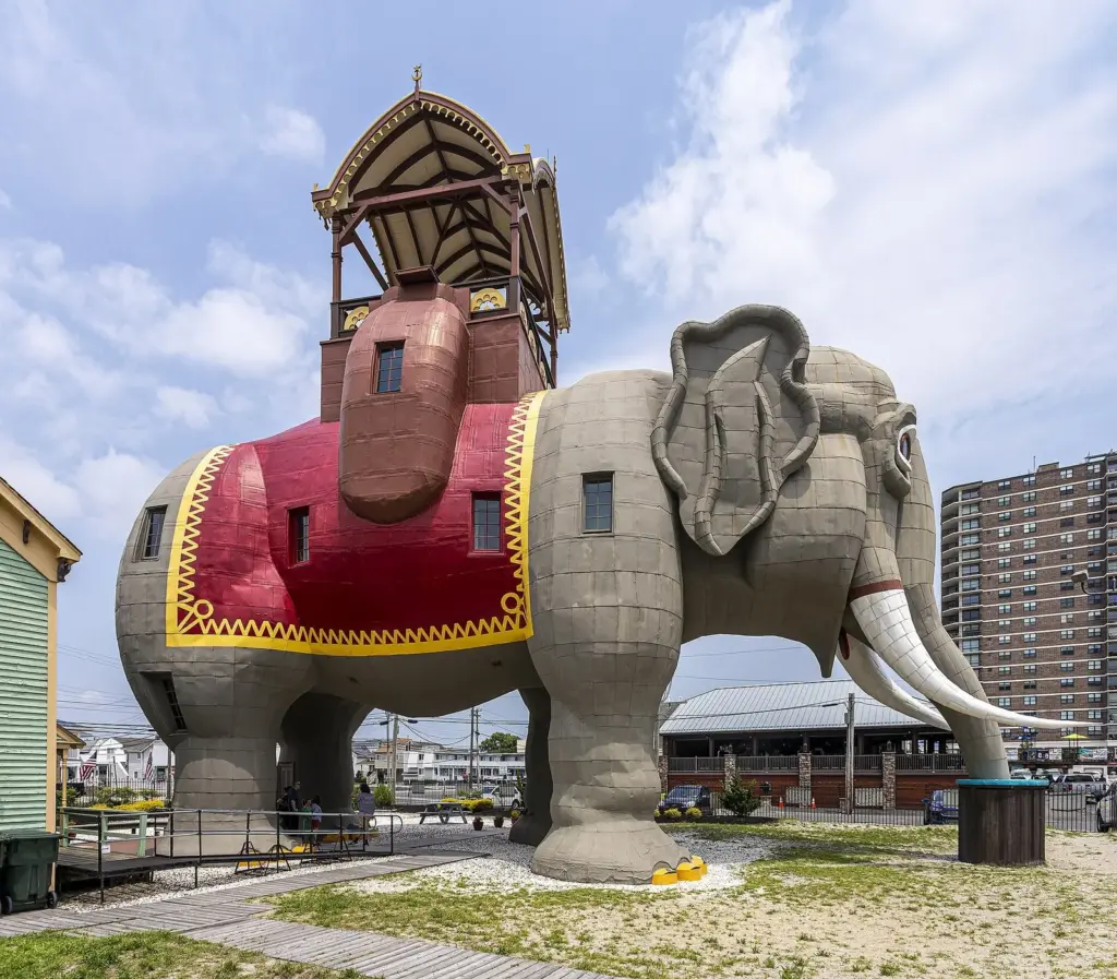 Lucy the Elephant, a six-story elephant building with a red and gold blanket and a canopied howdah, standing in a sandy park