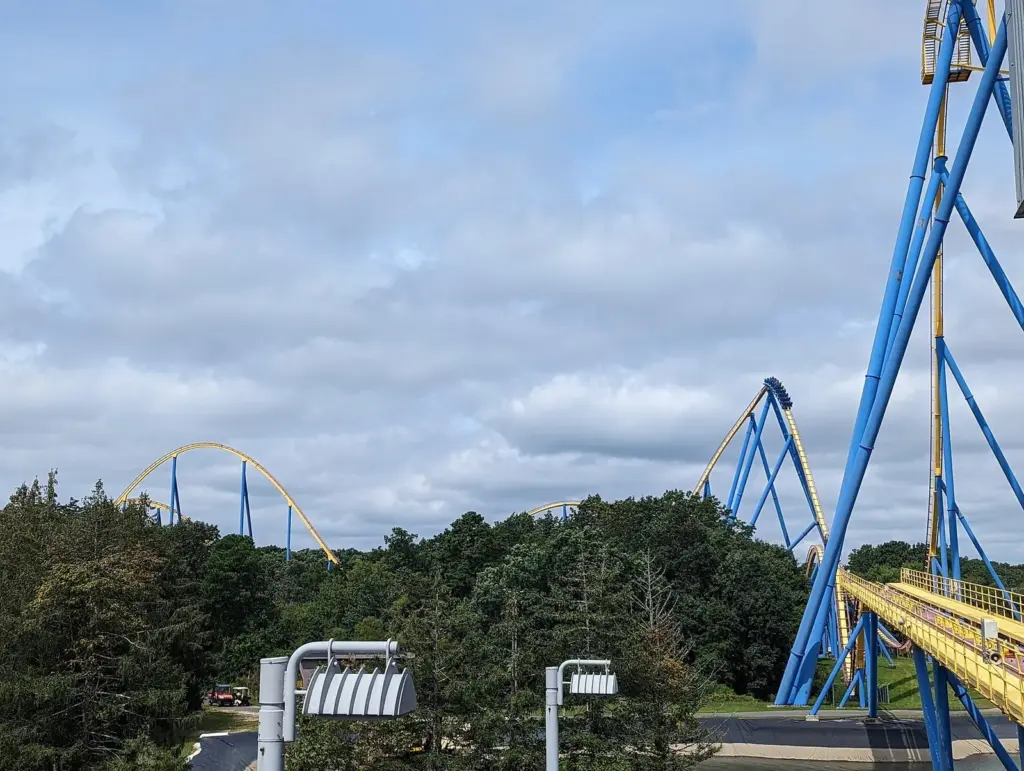 The blue supports and yellow track of Nitro's airtime hills rising above a line of pine trees