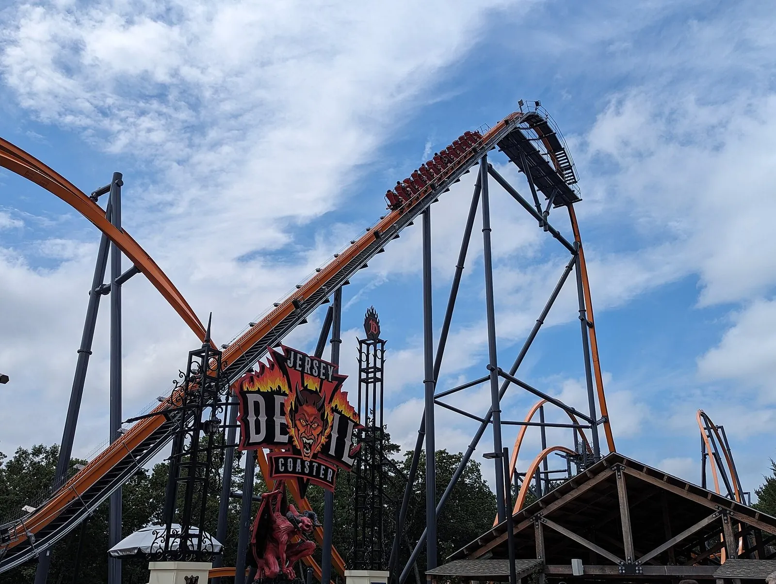 The orange track of the Jersey Devil Coaster climbing its first hill above the ride's entrance sign at Six Flags Great Adventure