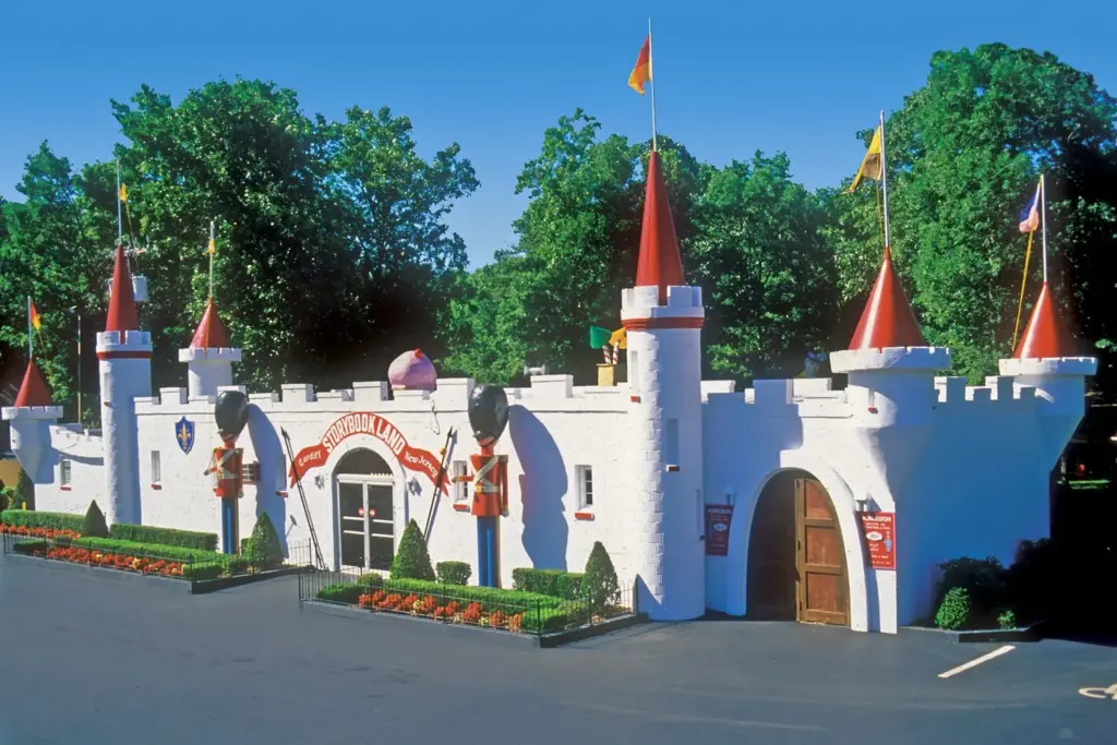 A white fairy-tale castle entrance with red turrets, pennants and toy-soldier figures at the gate