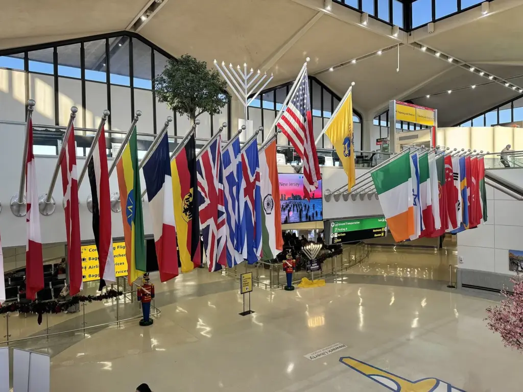 Rows of national flags hanging over a terminal hall decorated for the winter holidays, with a large menorah and toy-soldier figures