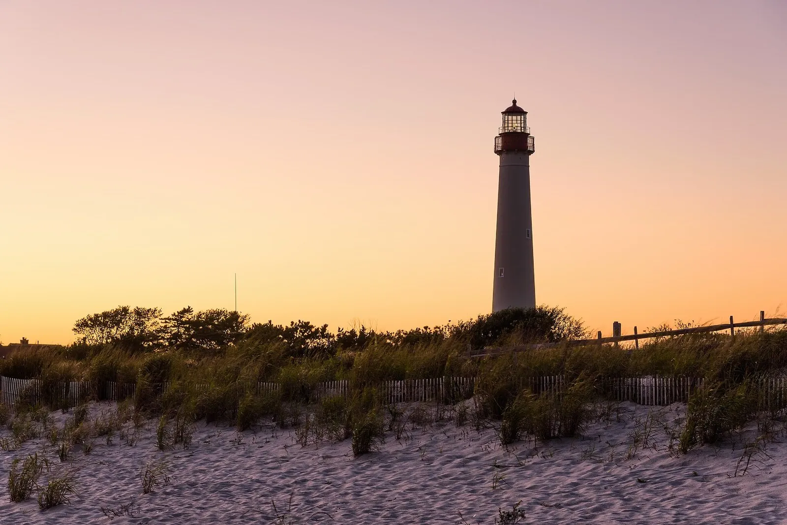 The Cape May Lighthouse at sunset above the dunes at Cape May Point, one of the best things to do in New Jersey