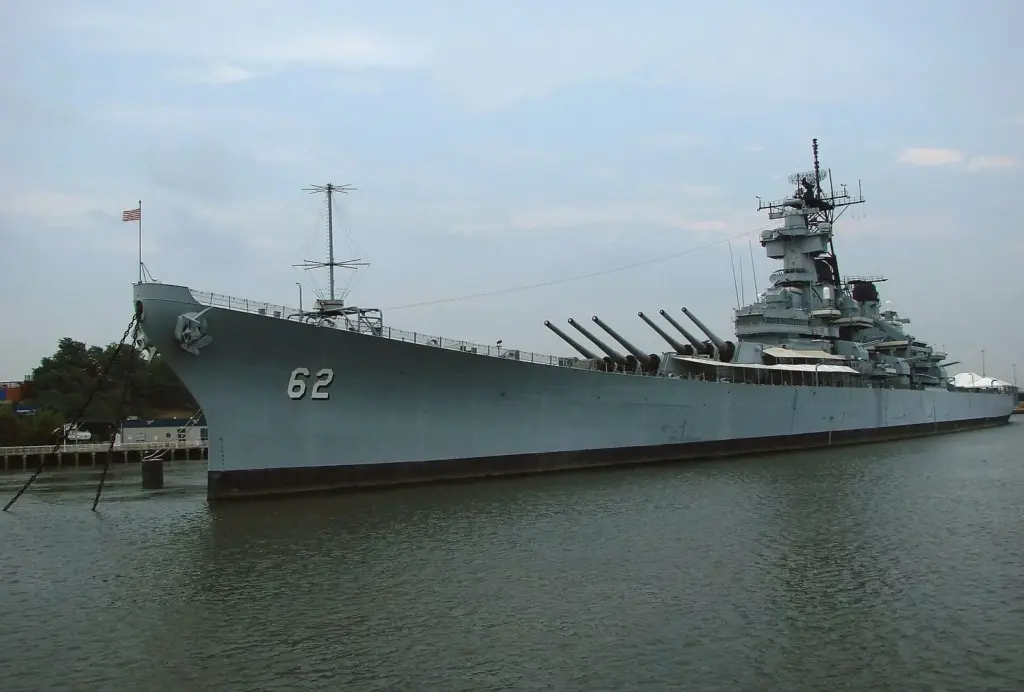 The gray hull and gun turrets of the battleship USS New Jersey, hull number 62, berthed along the Camden waterfront