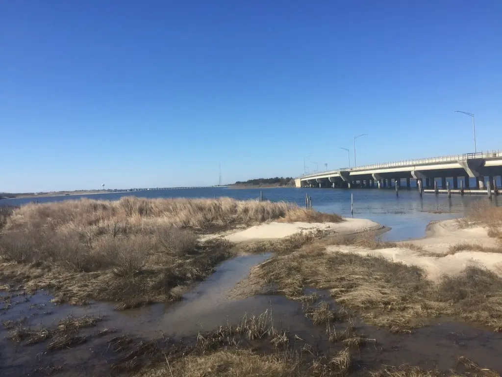 Brown marsh grass, sandbars and tidal pools at Corson's Inlet State Park, with the concrete Ocean Drive bridge to Strathmere stretching across the inlet on the right