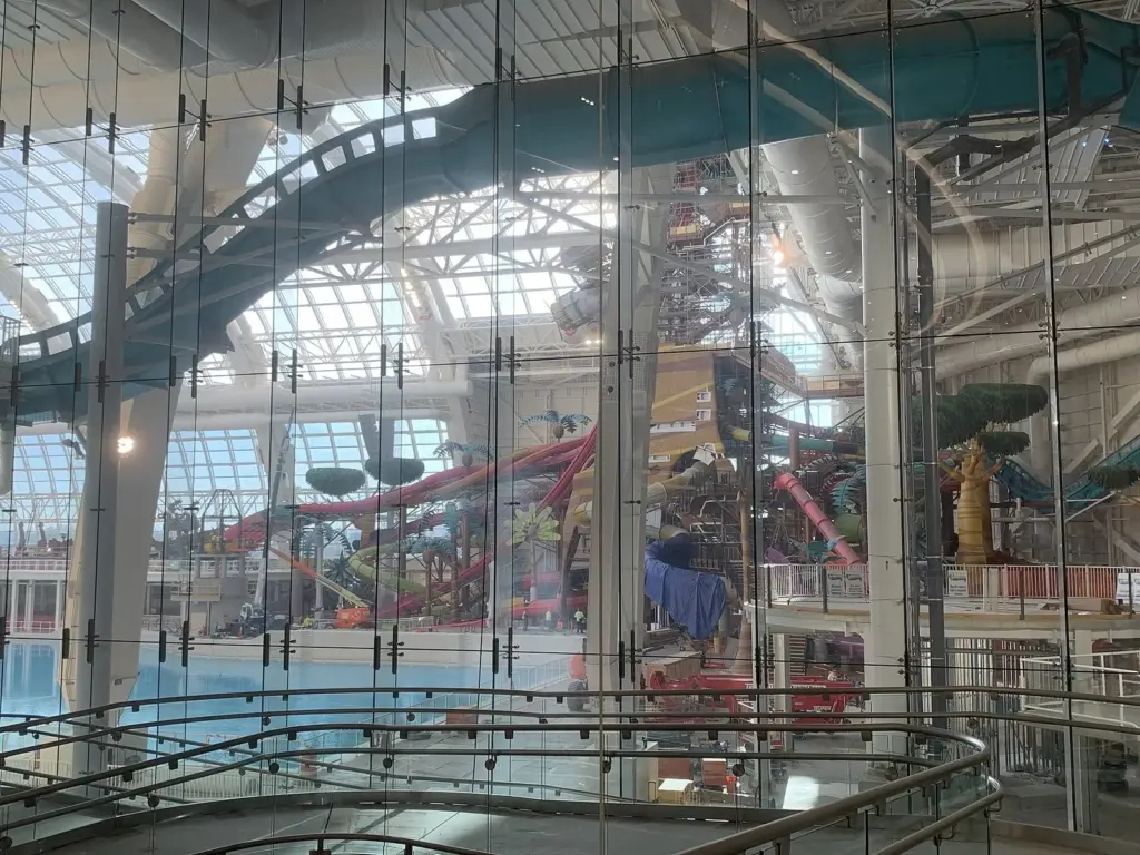 Colorful water slides, a model airplane and a slide tower seen through tall glass panels inside American Dream's indoor water park