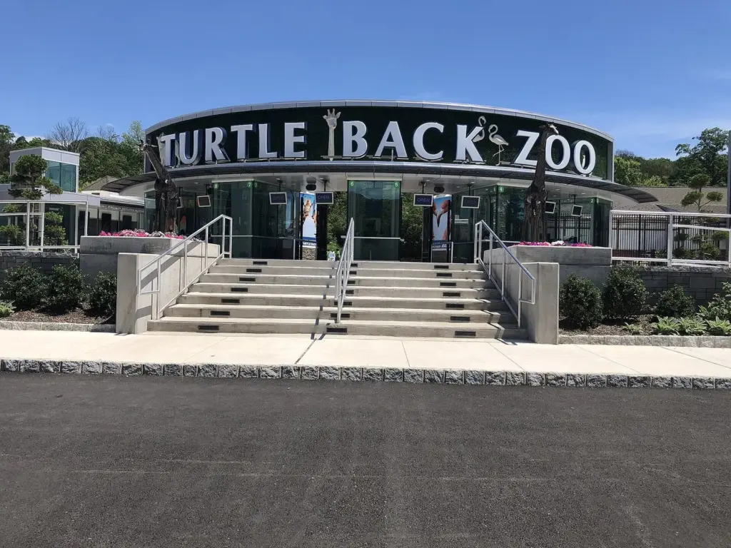 The curved entrance building of Turtle Back Zoo with large letters spelling the zoo's name above a wide flight of steps and planters